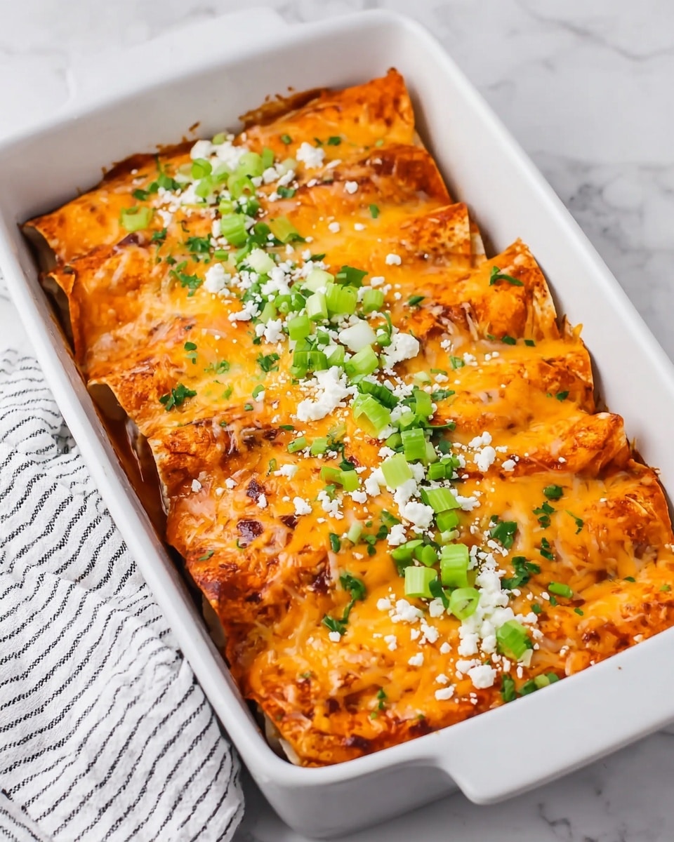 The image shows a white rectangular baking dish filled with five enchiladas placed side by side. Each enchilada is covered with a melted layer of orange and yellow cheese, which has some browned spots from baking. The enchiladas are topped with chopped green onions and crumbled white cheese scattered across the center. The dish sits on a white marbled surface with a white and black striped cloth on the left edge. The close-up focus captures the details and texture of the melted cheese and toppings. photo taken with an iphone --ar 4:5 --v 7