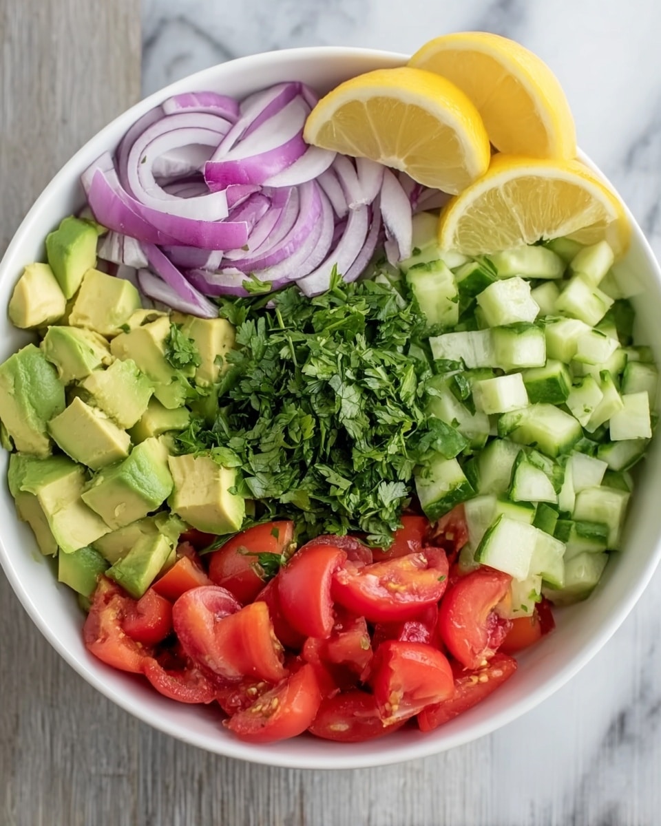 A white bowl sits on a white marbled surface, filled with five distinct layers of fresh vegetables. Starting from the left side, there are light green chunks of avocado, next to thin slices of purple onion. Above the onion is a heap of small green cucumber pieces with textured skin visible, occupying almost the top half of the bowl. At the center, a pile of finely chopped bright green cilantro covers part of all nearby layers. On the right side of the bowl, vibrant red tomato chunks with juicy interior are arranged. Two halves of a yellow lemon rest on the surface near the top right of the bowl. Photo taken with an iphone --ar 4:5 --v 7