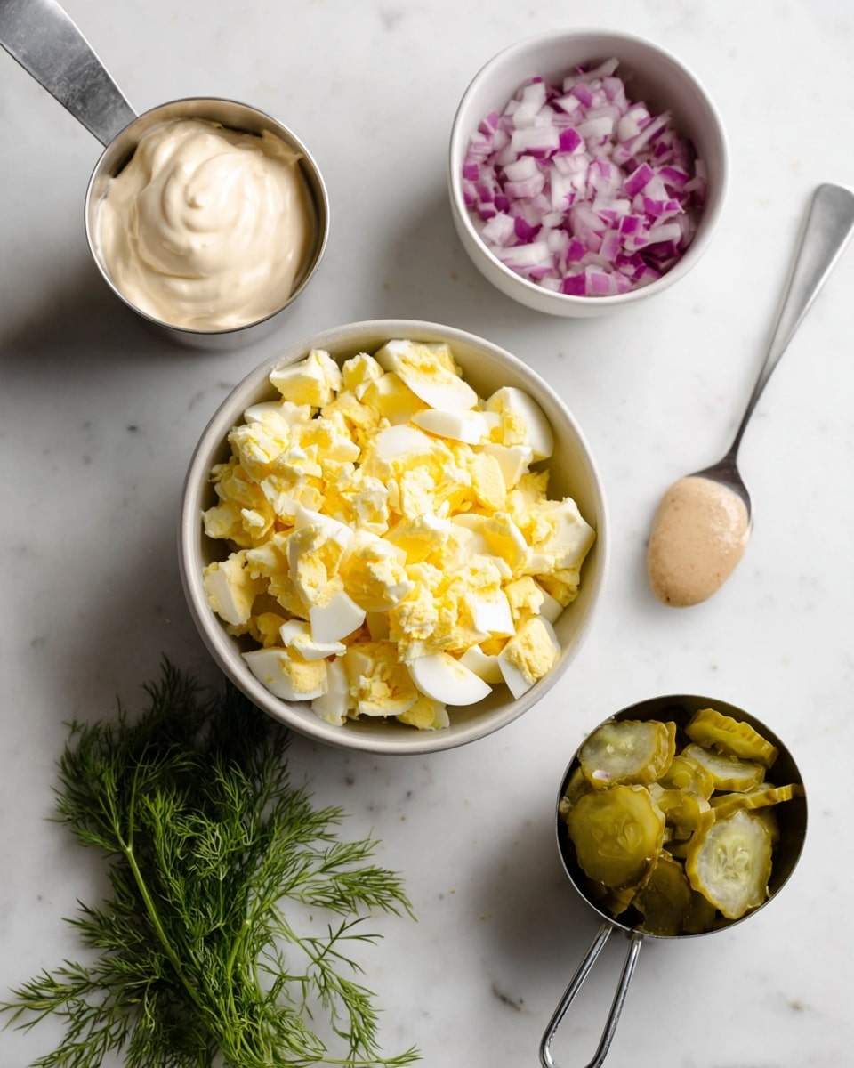 The image shows several ingredients on a white marbled surface: in the center is a bowl with chopped boiled eggs, with white and bright yellow pieces mixed together, filling the bowl almost to the top; behind it to the left is a metal cup filled with creamy white mayonnaise, slightly spread on top; behind to the right is a white bowl with finely chopped red onions, showing white and purple colors; at the front right is a metal measuring cup filled with chopped pickles, showing yellow and green pieces; in between is a small metal spoon with a dollop of mustard that is light brownish-yellow; fresh dill sprigs with green, delicate leaves are to the front left; the setup is clean and simple, focused on natural colors and textures of the ingredients, photo taken with an iphone --ar 4:5 --v 7