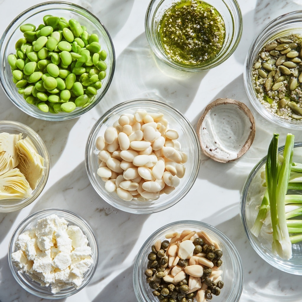 Several clear glass bowls are arranged on a white marbled surface, each holding a different ingredient. At the top left, a bowl filled with bright green edamame beans. To the top right, a bowl with a green herb dressing that has a slightly oily texture. In the center, a bowl filled with smooth, pale white beans. Towards the bottom left, there is one bowl with pale yellow artichoke pieces and below is a bowl with crumbly, white feta cheese. Smaller bowls contain round, green capers, whole garlic bulb, pine nuts, and long green scallions are placed vertically on the right side. The bright natural light creates soft shadows around the bowls, showing clear texture and fresh colors. Photo taken with an iphone --ar 4:5 --v 7