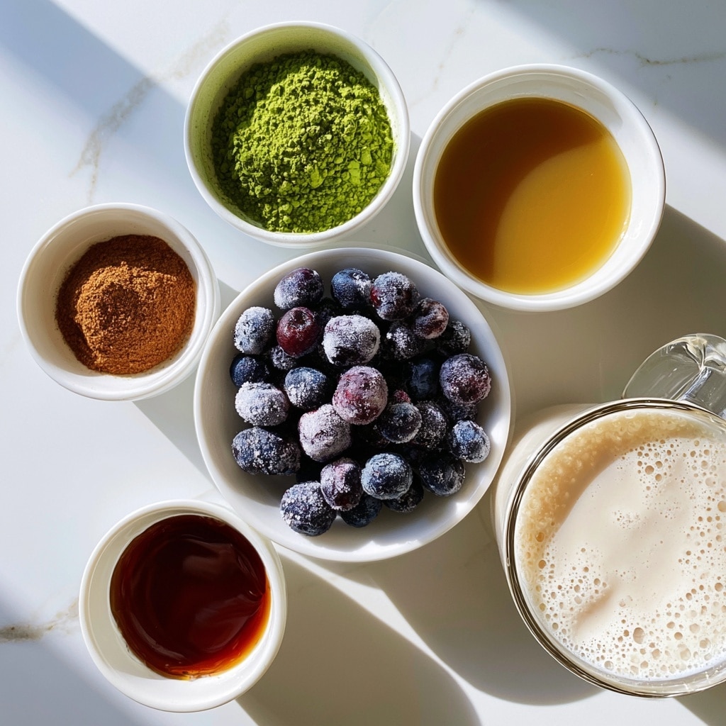 A top view of five small white bowls and one clear glass mug arranged on a white marbled surface. The largest white bowl, centered slightly lower, holds many frozen blueberries covered with frosty white bits, dark blue and purple in color. Above it, a small white bowl contains bright green matcha powder with a fine texture. Next to matcha, another small white bowl is filled with golden brown vanilla liquid, smooth and light-reflective. To the left, a tiny white bowl (photographed as if wooden, now white) holds ground cinnamon, warm brown and finely ground. Below the blueberries, a small white bowl has thick, shiny maple syrup in dark reddish-brown shades. To the right bottom corner, a clear glass mug shows creamy off-white oat milk topped with delicate bubbles, the glass handle visible to the right. The image is well-lit with soft natural light and shadows. Photo taken with an iphone --ar 4:5 --v 7