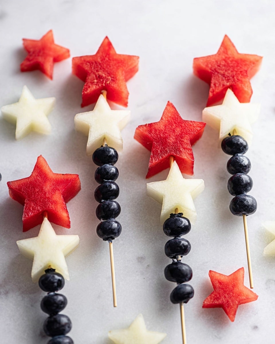 The image shows fruit skewers arranged like a small bouquet on a white marbled surface. Each skewer has three layers: dark purple blueberries at the bottom, a middle layer of pale cream star-shaped fruit, and a top layer of bright red star-shaped watermelon pieces. Around the bouquet are two white plates, one holding light yellow star-shaped fruit and the other holding several red star-shaped watermelon pieces. A clear bowl with dark blueberries is seen at the bottom left corner. The colors are bright and fresh with a clean, simple look. Photo taken with an iphone --ar 4:5 --v 7