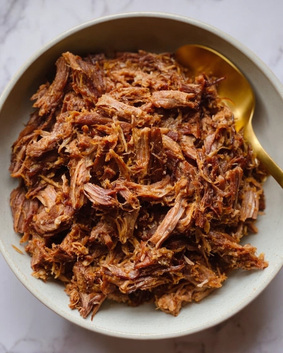 A white bowl filled with shredded brown cooked meat, showing a mix of light and dark brown tones and fibrous texture with soft, uneven pieces piled up evenly. A gold spoon rests on the edge of the bowl, adding a touch of shine. The bowl is set on a white marbled surface. Photo taken with an iphone --ar 4:5 --v 7