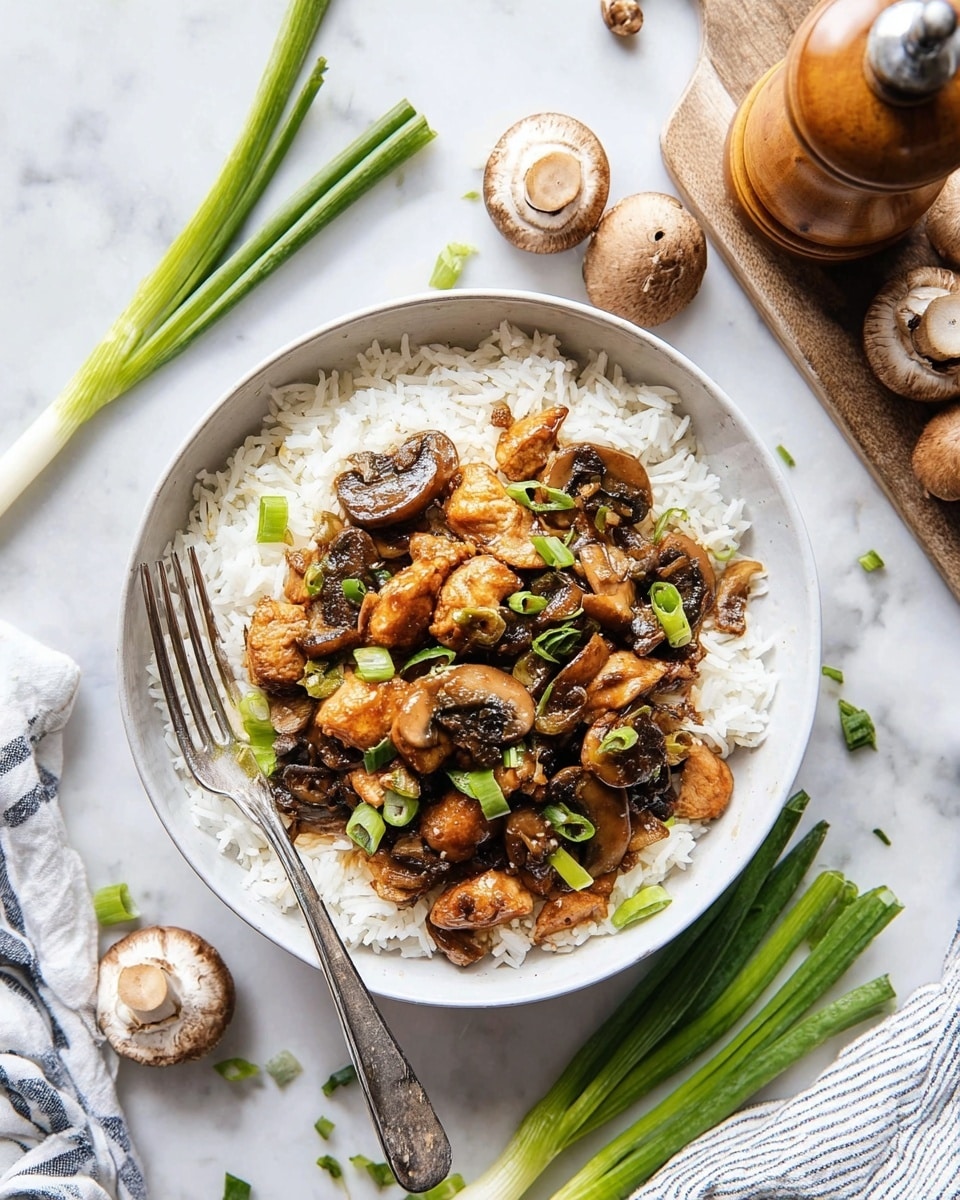 A white bowl filled with two layers: the bottom layer is fluffy white rice, and the top layer is a mix of browned chicken pieces and sautéed dark brown mushrooms with green onion slices scattered throughout. A silver fork rests inside the bowl on the left side. Around the bowl, there are some fresh whole mushrooms and green onion stalks on a white marbled surface, with a wooden pepper grinder on a small wooden board at the top right. A white and blue striped cloth is partially visible in the bottom left corner. Photo taken with an iphone --ar 4:5 --v 7
