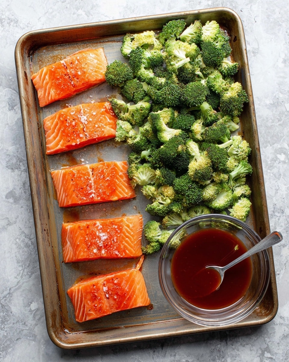 A metal baking tray holds a fresh salmon fillet on the left side, cut into four thick horizontal pieces with a bright orange color and small white lines of fat, lightly sprinkled with salt and pepper. Above the salmon, there is a large area filled with chopped broccoli florets, vibrant green with some light browning, spread loosely. On the bottom right corner of the tray rests a clear white bowl filled with a deep reddish-brown sauce, with a silver spoon inside it. The tray is placed on a white marbled textured surface. photo taken with an iphone --ar 4:5 --v 7