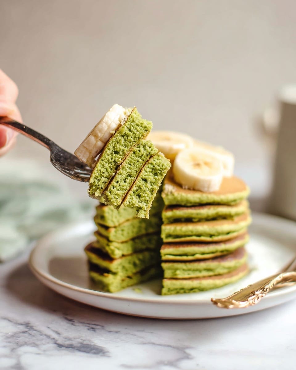 A stack of six green pancakes sits on a white plate with a white marbled surface below, topped with three slices of banana. A woman's hand holds a fork lifting a bite of pancake showing a soft, textured inside. The pancakes are thick and fluffy with a consistent green color throughout. The scene has a soft, bright background with a light and airy feel. photo taken with an iphone --ar 4:5 --v 7