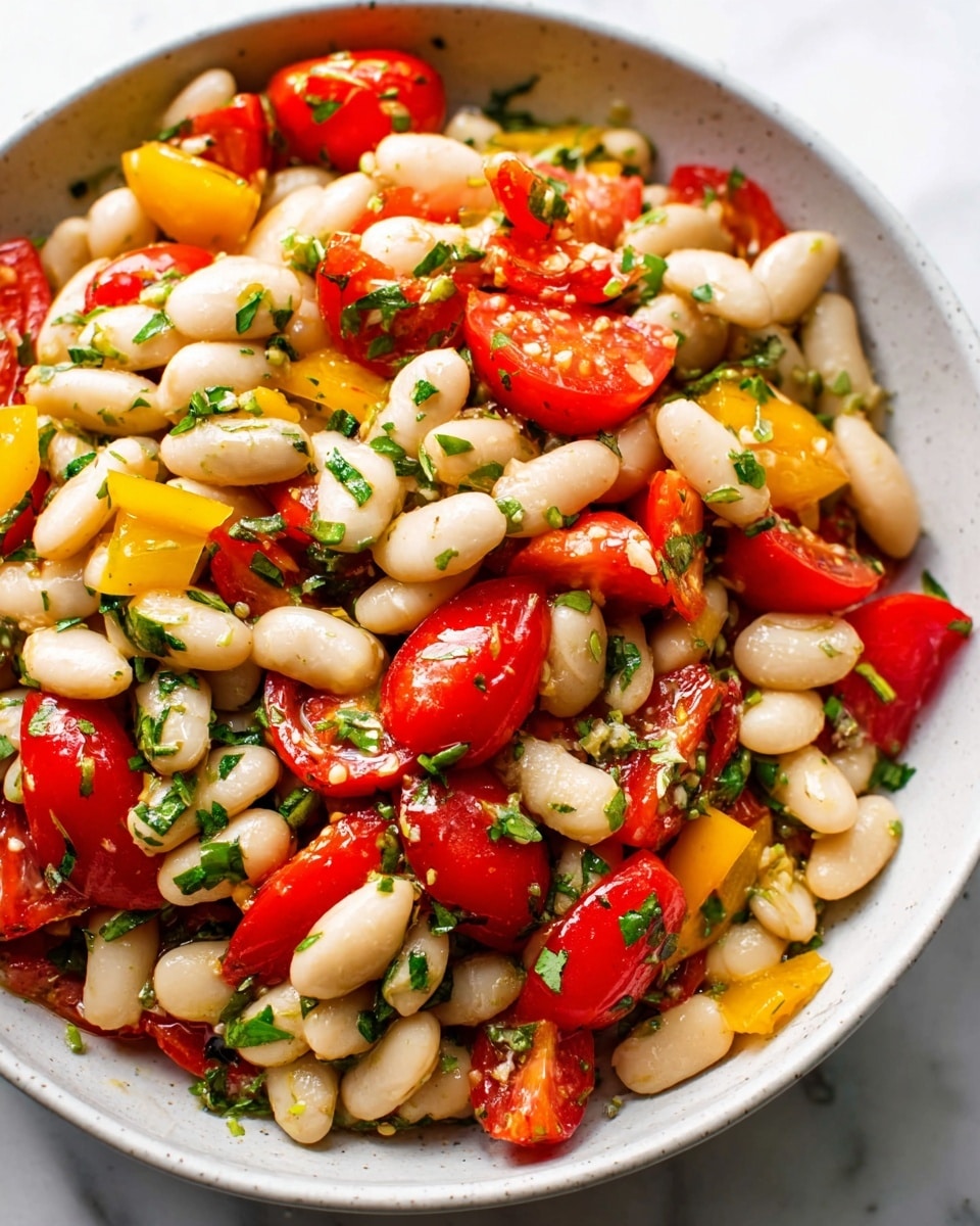 A close-up view of a white bowl filled with a colorful bean salad. The salad has three main layers: plump, smooth white beans as the base layer, bright red grape tomatoes cut into halves and quarters scattered evenly on top, and small pieces of yellow bell pepper mixed throughout. Fresh green chopped herbs are sprinkled all over the salad, adding a fresh texture. The bowl is placed on a white marbled surface. photo taken with an iphone --ar 4:5 --v 7