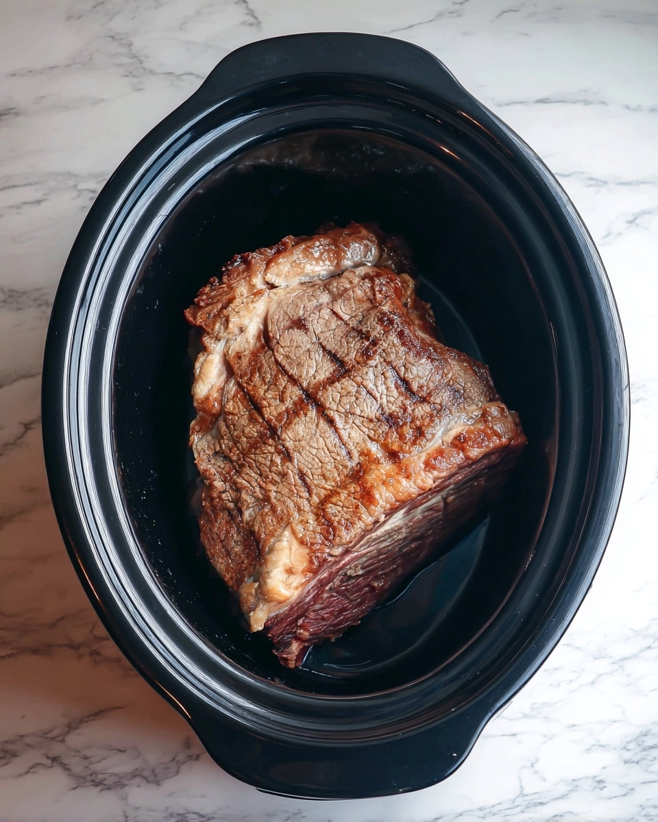 A large piece of cooked meat with a brown, slightly crispy surface and some lighter areas of fat rests in a black oval slow cooker. The meat shows clear grill marks and texture from cooking. The slow cooker sits on a white marbled surface, and the inside of the cooker is shiny and smooth, reflecting some light. Photo taken with an iphone --ar 4:5 --v 7