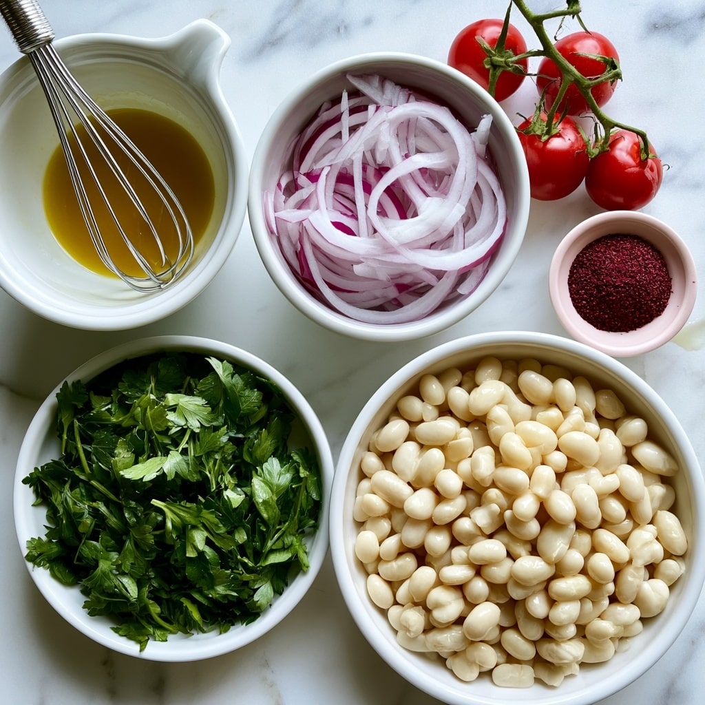 The image shows various fresh ingredients neatly arranged on a white marbled surface. There is a white ceramic bowl with a metal whisk inside, holding a golden-yellow salad dressing. Next to it, a white bowl contains thinly sliced red onions with their pale purple and white colors visible. Below that, another white bowl is filled with vibrant green parsley leaves. To the right, a vine with four shiny red tomatoes rests directly on the surface. A small pale pink bowl holds a deep red spice labeled sumac. Lastly, a large white bowl is full of plump, creamy white beans, making a rich contrast with the other vibrant ingredients. Photo taken with an iphone --ar 4:5 --v 7