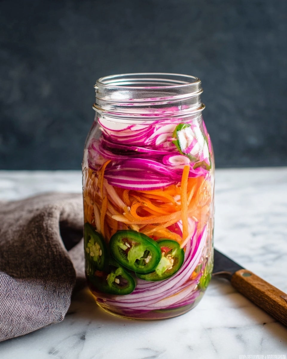 A clear glass jar is filled with colorful pickled vegetables in layers, placed on a white marbled surface with a grey cloth nearby. At the bottom layer, there are thinly sliced purple and white onions with a slightly translucent texture. Above this, bright orange carrot strips add a fine, crunchy texture. Next, sliced green jalapeño peppers with visible seeds form the middle layer, adding a fresh green color. The top layer contains light pink radish slices, thin and nearly translucent, floating in a clear pickling liquid. The jar is open and standing upright with a wooden handle knife partly visible on the side. Photo taken with an iphone --ar 4:5 --v 7