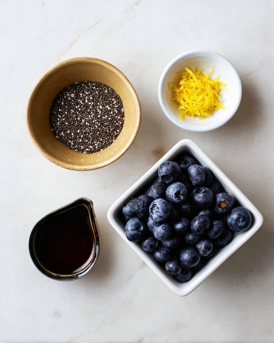 The image shows four small containers arranged on a white marbled surface. On the top left, a tan bowl is filled with small black and white chia seeds. To the right of it, a small white dish contains a heap of yellow lemon zest. Below the tan bowl, a small black bowl holds a dark brown liquid, likely maple syrup. On the right side, a white square bowl is full of plump, dark blue blueberries. The overall setup is simple with a light, clean look. photo taken with an iphone --ar 4:5 --v 7