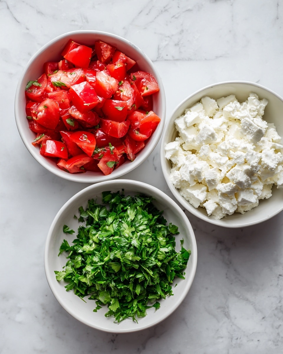 The image shows three small white bowls on a white marbled surface. The top left bowl holds bright red chopped fresh tomatoes with a juicy texture. The top right bowl contains crumbly white feta cheese, looking soft and uneven in shape. The bottom center bowl is filled with fresh chopped green parsley, finely chopped and vibrant. The bowls are arranged in a triangular shape on the surface. photo taken with an iphone --ar 4:5 --v 7