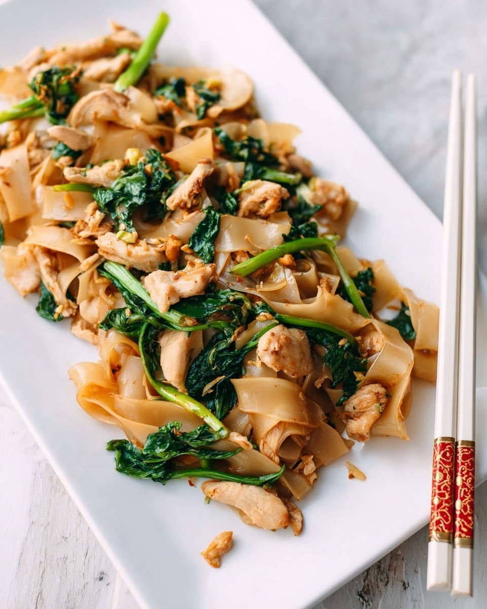 The dish shows a white square plate filled with wide flat rice noodles that are light brown and slightly shiny, layered with small pieces of light tan chicken slices, and vibrant dark green leafy vegetables with some stems that have a slightly glossy texture. The ingredients are mixed together with a light sauce giving a moist look, and a pair of wooden chopsticks with red Asian characters lies diagonally on the plate’s bottom edge. The plate sits on a white marbled surface with a brown cloth napkin featuring thin black stripes just behind it. Photo taken with an iphone --ar 4:5 --v 7