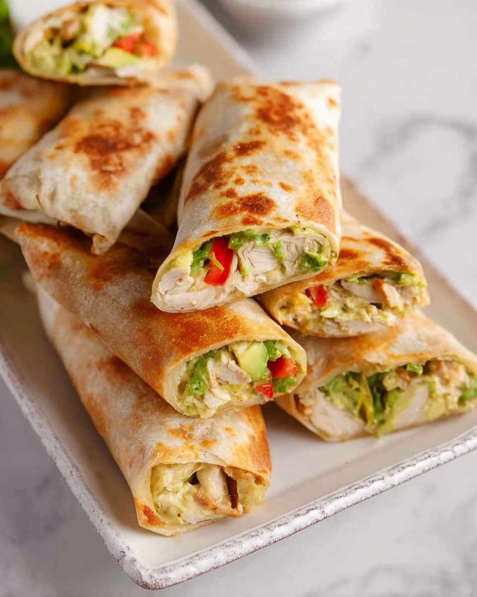 The image shows several folded wraps placed in a stack on a white rectangular plate with a subtle textured rim. Each wrap has a golden-brown, slightly crispy outer layer with light spots indicating gentle baking. Inside, there are multiple fillings visible: chunks of light beige chicken, bright green lettuce or avocado pieces, small bits of red bell pepper, and some creamy pale yellow sauce. The wraps are cut in halves, revealing the colorful and textured layers inside, and are arranged close together on a white marbled surface. Photo taken with an iphone --ar 4:5 --v 7