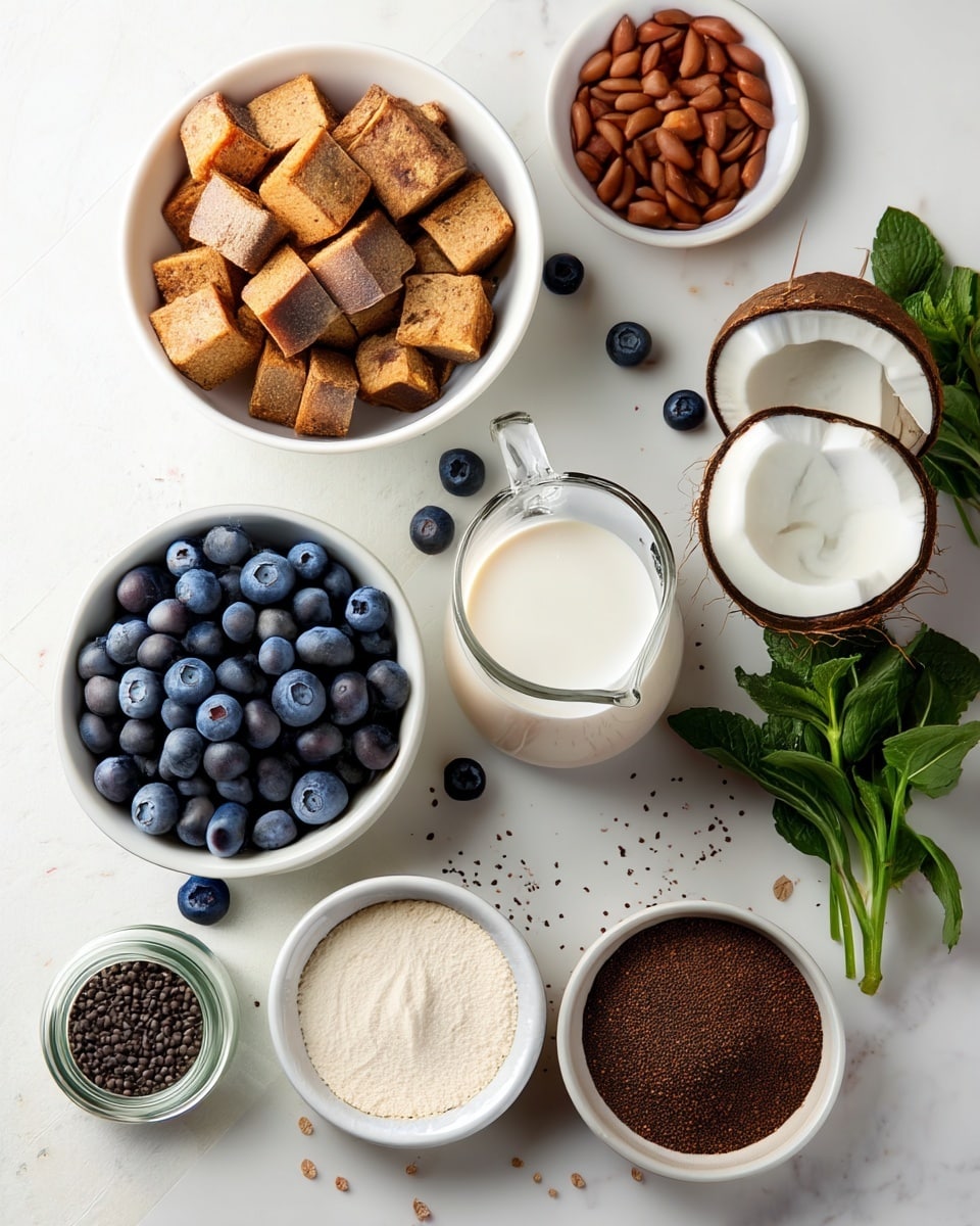 The image shows several white bowls and a clear glass jug arranged on a white marbled surface. The top left bowl holds medium-sized, golden brown cubes with a rough texture. To its right, another white bowl contains small, reddish-brown nuts. Below, a large white bowl is full of fresh, round blueberries with a deep blue color. A clear glass jug in the center holds a smooth, white liquid. Nearby, two halves of a brown coconut with white flesh are placed. In the middle, a white bowl contains a fine, off-white powder. To the bottom left, a small glass jar holds tiny dark seeds, and next to it is a white bowl filled with dark brown coarse powder. On the right bottom corner, a white bowl shows chunky light brown pieces. Fresh green mint leaves are placed near the right edge. Blueberries are scattered across the surface around the bowls. Photo taken with an iphone --ar 4:5 --v 7