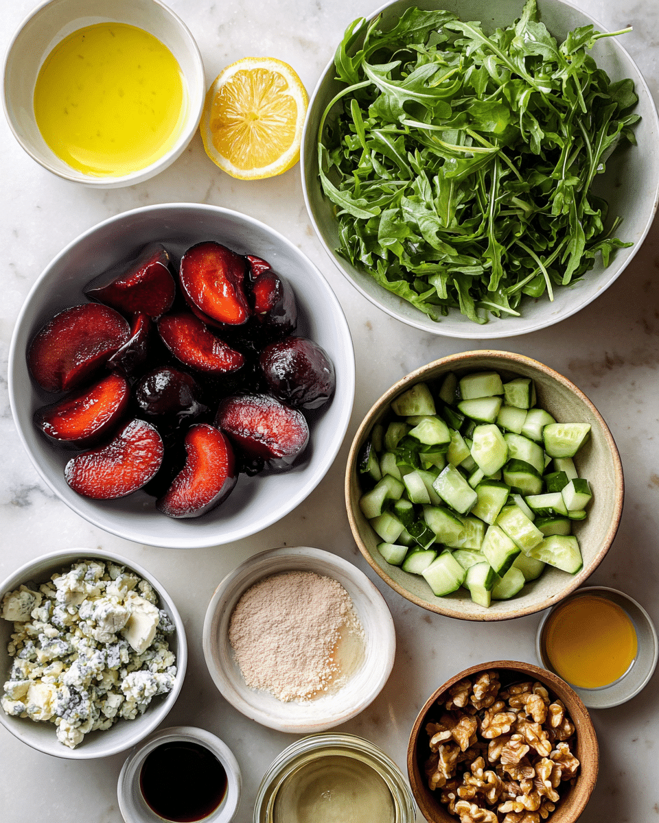 The image shows several separate white and brown bowls and small dishes arranged on a white marbled surface. In the center, a white bowl is filled with dark red sliced plums showing their shiny and smooth texture, while above it, another white bowl is full of fresh green arugula leaves with a slightly ruffled texture. To the left, a small white bowl contains yellow oil, and next to it is a white dish with one slice of lemon. A bowl with blue-veined crumbled cheese is seen upper left in a white bowl. On the bottom right, a brown bowl holds chopped green cucumbers with their skin. Near the cucumbers, there is a small white dish with a light-colored powder and a small bowl with a golden liquid. There are also small bowls containing dark balsamic vinegar and brown walnuts scattered around. The overall look shows fresh healthy ingredients prepared for a salad photo taken with an iphone --ar 4:5 --v 7