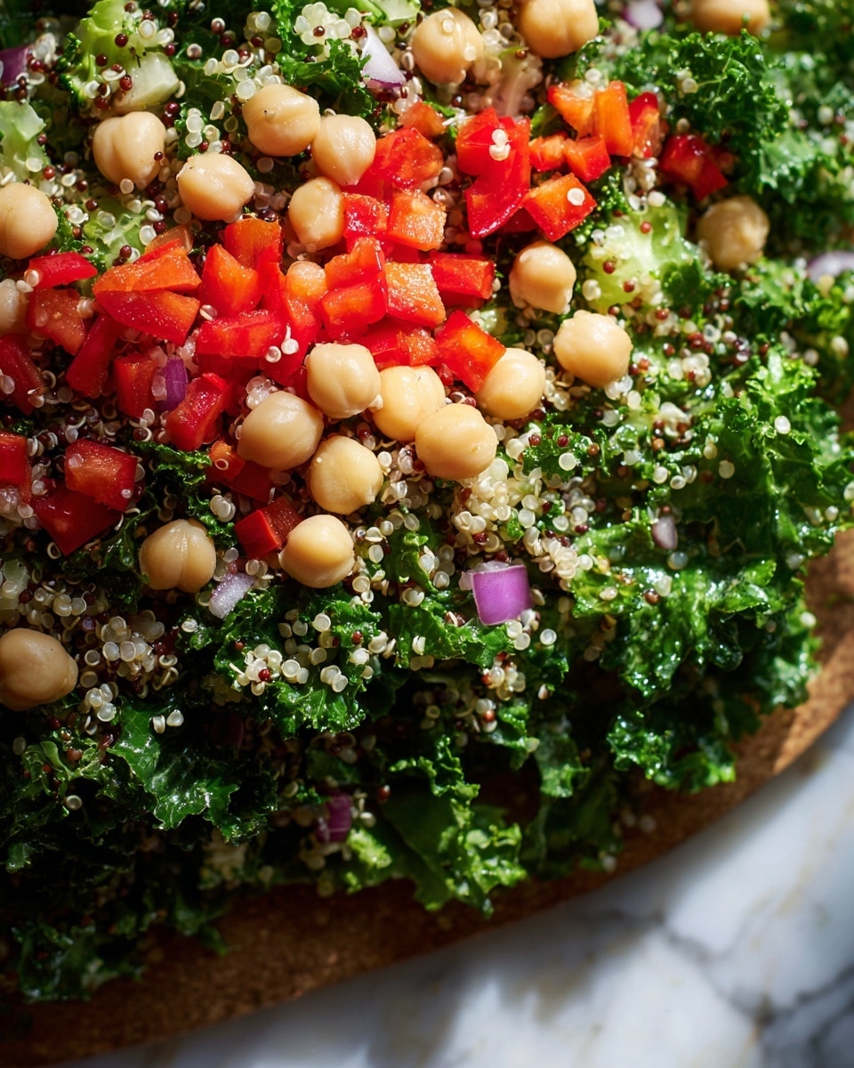 A close-up view of a salad with three main layers: the base is dark green kale leaves, curly and textured, mixed evenly with small white and red quinoa grains scattered throughout. Above that, round, smooth beige chickpeas are spread on the salad, adding a solid, soft texture. On the top layer, small, bright red diced bell pepper pieces are sprinkled evenly across, adding vibrant color contrast. There are also small bits of purple onion and tiny broccoli florets mixed in. The whole salad is shown on a white marbled surface, with natural light highlighting the fresh colors and textures. photo taken with an iphone --ar 4:5 --v 7