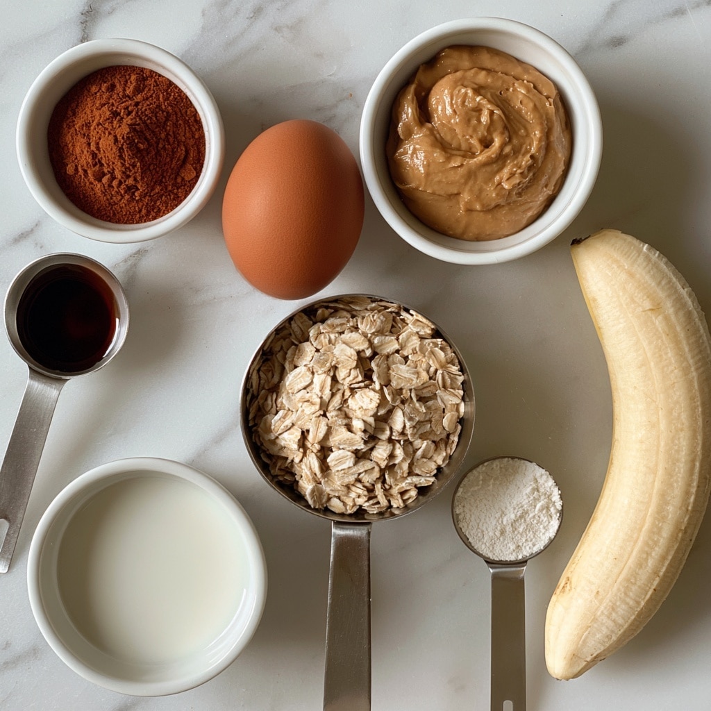 A white marbled surface holds an arrangement of baking ingredients, each clearly labeled: a whole brown egg sits in the center, beside a small white bowl filled with smooth, light brown nut butter; below the egg is a metal measuring cup with pale tan rolled oats. To the left, there is a small white bowl holding reddish-brown cinnamon powder and a metal measuring spoon containing dark vanilla extract. Below is a small white bowl of white milk. On the right side, a half-peeled light yellow banana rests near a metal measuring spoon holding fine white baking powder. The composition is neat, with each item spaced evenly. Photo taken with an iphone --ar 4:5 --v 7