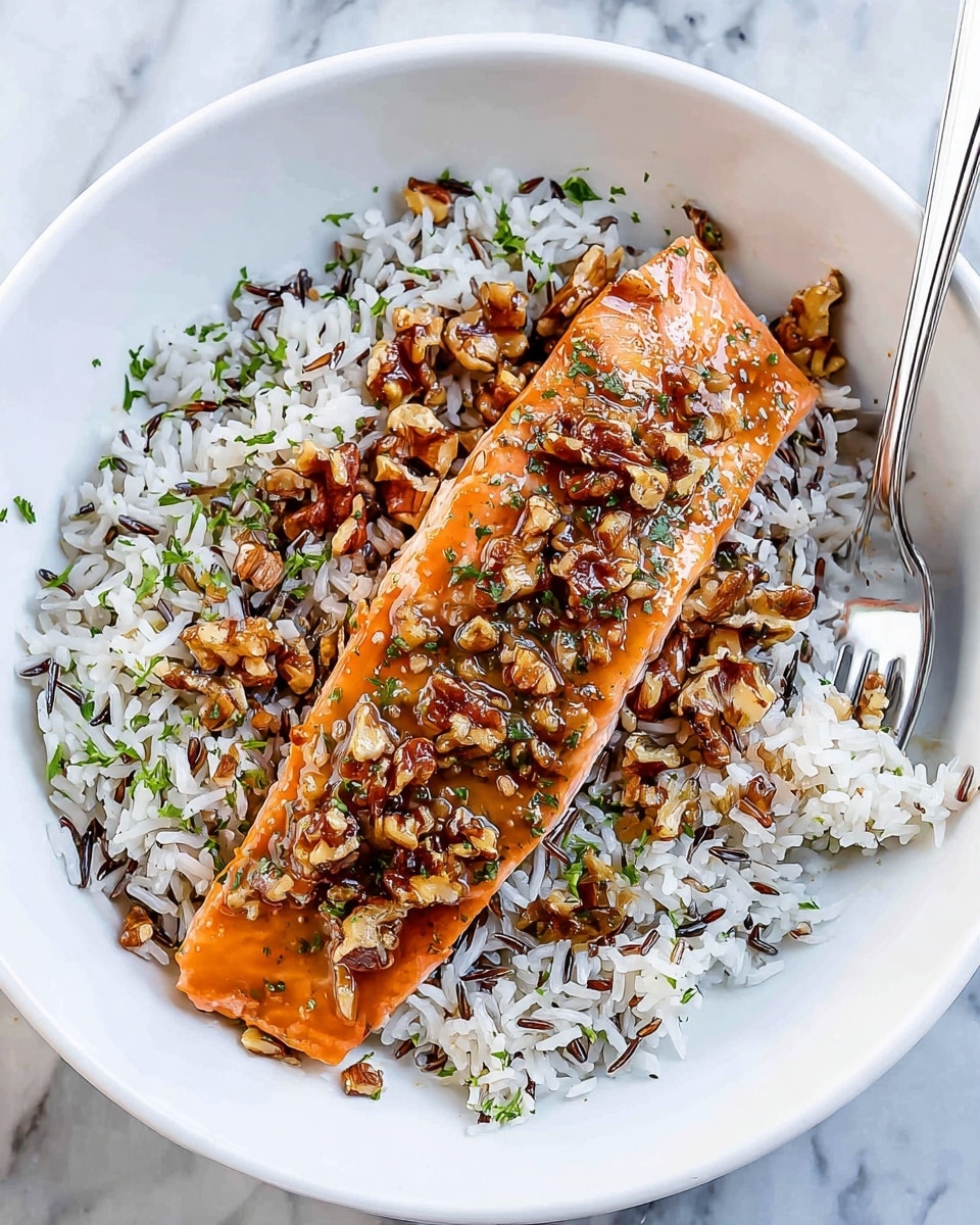 A white round plate on a white marbled surface holds a serving of wild rice and white rice mix as the base layer with a fluffy texture and scattered green herb bits. On top, a single piece of cooked salmon with a soft orange color rests in the center. The salmon is covered with a glossy sauce containing chopped walnuts and green herbs, adding a shiny, textured layer over the fish. A silver fork is placed on the right side of the plate, partially on the rice. photo taken with an iphone --ar 4:5 --v 7