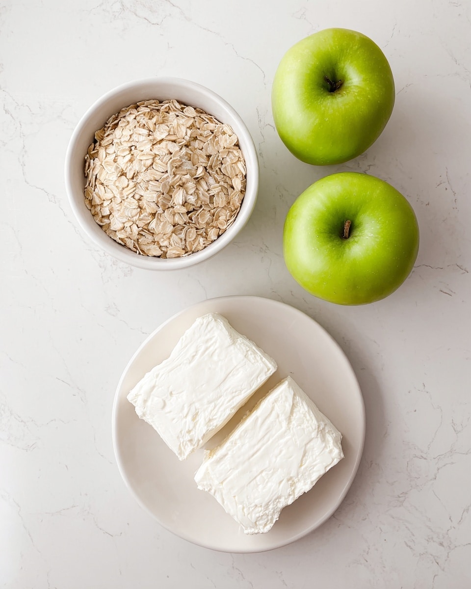 Two layers are shown in the image: the top layer has a white bowl filled with light brown rolled oats, and just below it, two bright green apples with smooth skin are placed side by side on a white marbled surface. At the bottom, part of a white plate holds a rectangular block of white cream cheese with a smooth and slightly textured surface, split into two pieces. Photo taken with an iphone --ar 4:5 --v 7