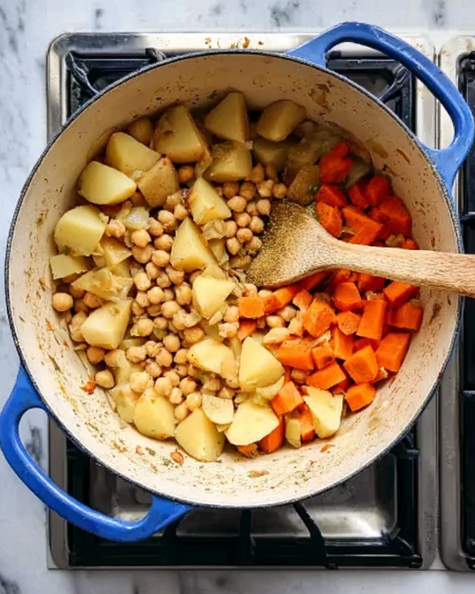A blue pot with white inside sits on a stove with a white marbled surface beneath. Inside the pot, there is a mix of cooked chickpeas, yellow potatoes cut into chunks and placed mostly on the left and center, and small pieces of orange carrots grouped mainly on the right side. A wooden spoon is lying inside the pot, resting on the stir-fry of vegetables near the edge. The colors inside include light yellow from the potatoes, light beige from the chickpeas, and bright orange from the carrots. The background and stove frame the pot neatly, making the ingredients clear and colorful. photo taken with an iphone --ar 4:5 --v 7