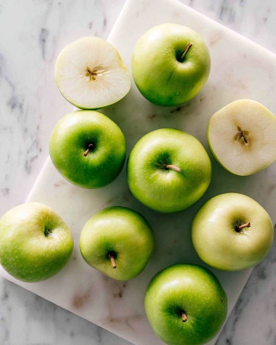 There are nine apples placed on a white marble cutting board, set on a white marbled surface. Six apples still have their green skin, smooth and shiny, while three apples are peeled, showing a pale, creamy white color with a slightly rougher texture where the skin is removed. The apples are randomly arranged, some touching each other, with stems still attached. Photo taken with an iphone --ar 4:5 --v 7