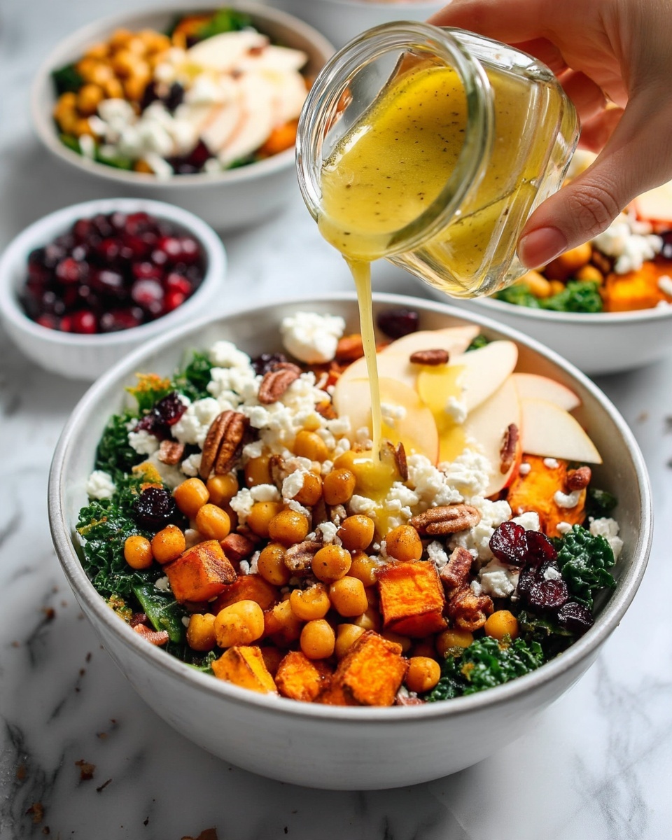The image shows a white bowl filled with a colorful layered salad on a white marbled surface. The bottom layer is dark green leafy kale, topped with bright orange cubes of roasted sweet potatoes. Above that are golden chickpeas scattered around. Thin slices of light yellow apple are placed on top, mixed with crumbly white goat cheese. Dark red dried cranberries and brown pecan nuts are scattered all over the salad. A light yellow dressing is being poured over the top from a small glass jar by a woman's hand. The scene is bright and fresh with more bowls of the same salad around the main bowl. photo taken with an iphone --ar 4:5 --v 7